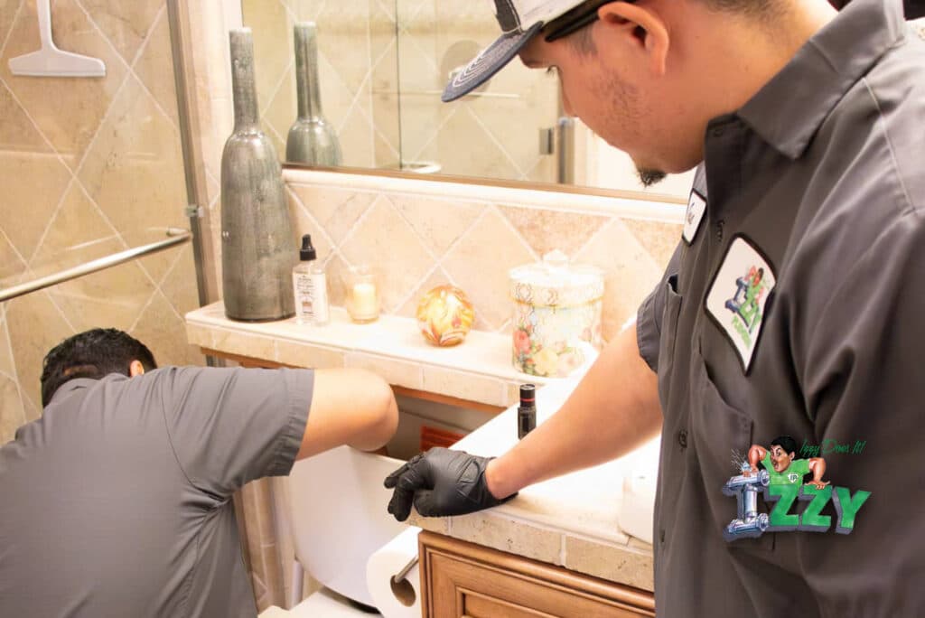 Plumbing technicians inspecting a toilet for potential issues, showcasing Izzy Plumbing's expertise in sewer line inspections and repairs.