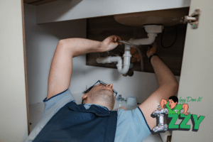 Plumber repairing pipes under kitchen sink