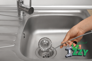 Hand using drain snake in kitchen sink